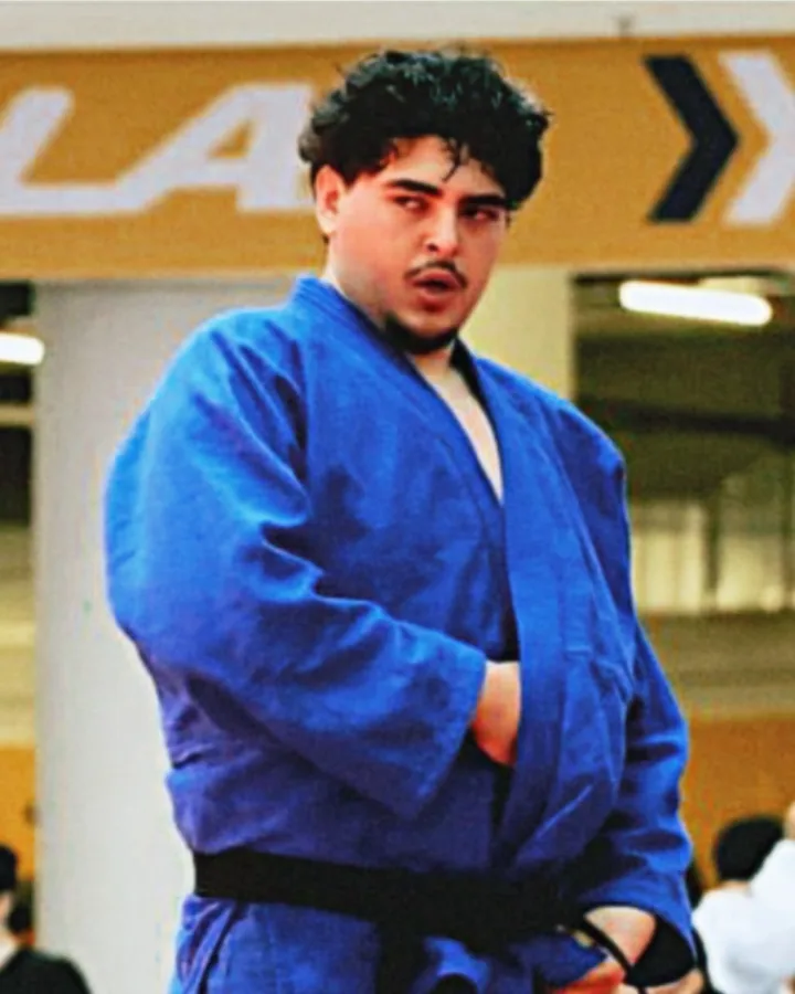 Coach Amine in a blue judo gi and black belt at a tournament