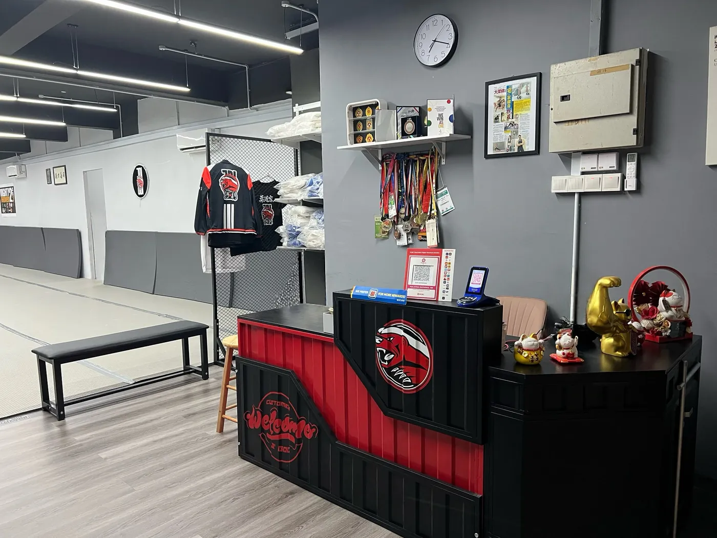 JDI Judo front desk in black and red with the badger logo, medals and trophies on the wall